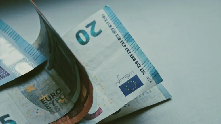 Dažāda nomināla eiro banknotes uz gaišas virsmas, kas simbolizē finansiālo stabilitāti un ECB lēmumus.