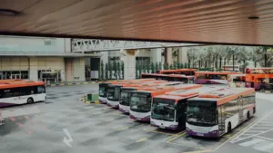 Autobusu parks ar vairākiem sabiedriskā transporta līdzekļiem gaida pasažierus uz izbraukšanu maršrutos