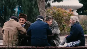 Senioru vīrieši apspriežas pie āra galda Alūksnes pasākuma tematikai atbilstošā mierīgā atmosfērā.