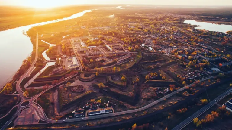 Putnisks skats uz Daugavpili un Daugavas upi zelta stundā vasaras vakarā.