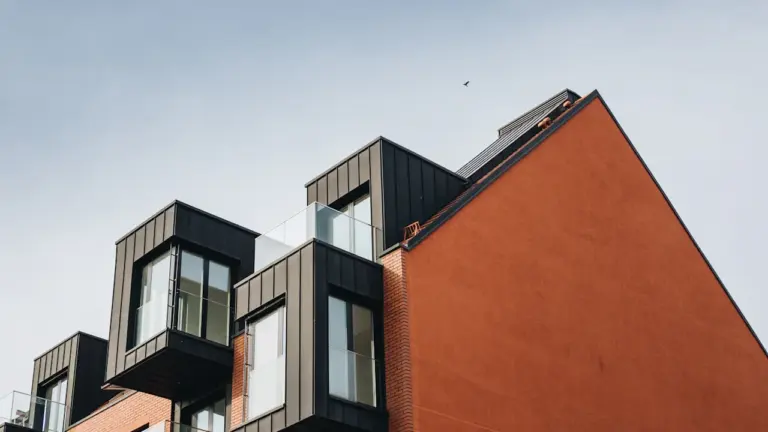 Mūsdienīga dzīvojamā ēka ar energoefektīvu fasādi un balkoniem pilsētas vidē.